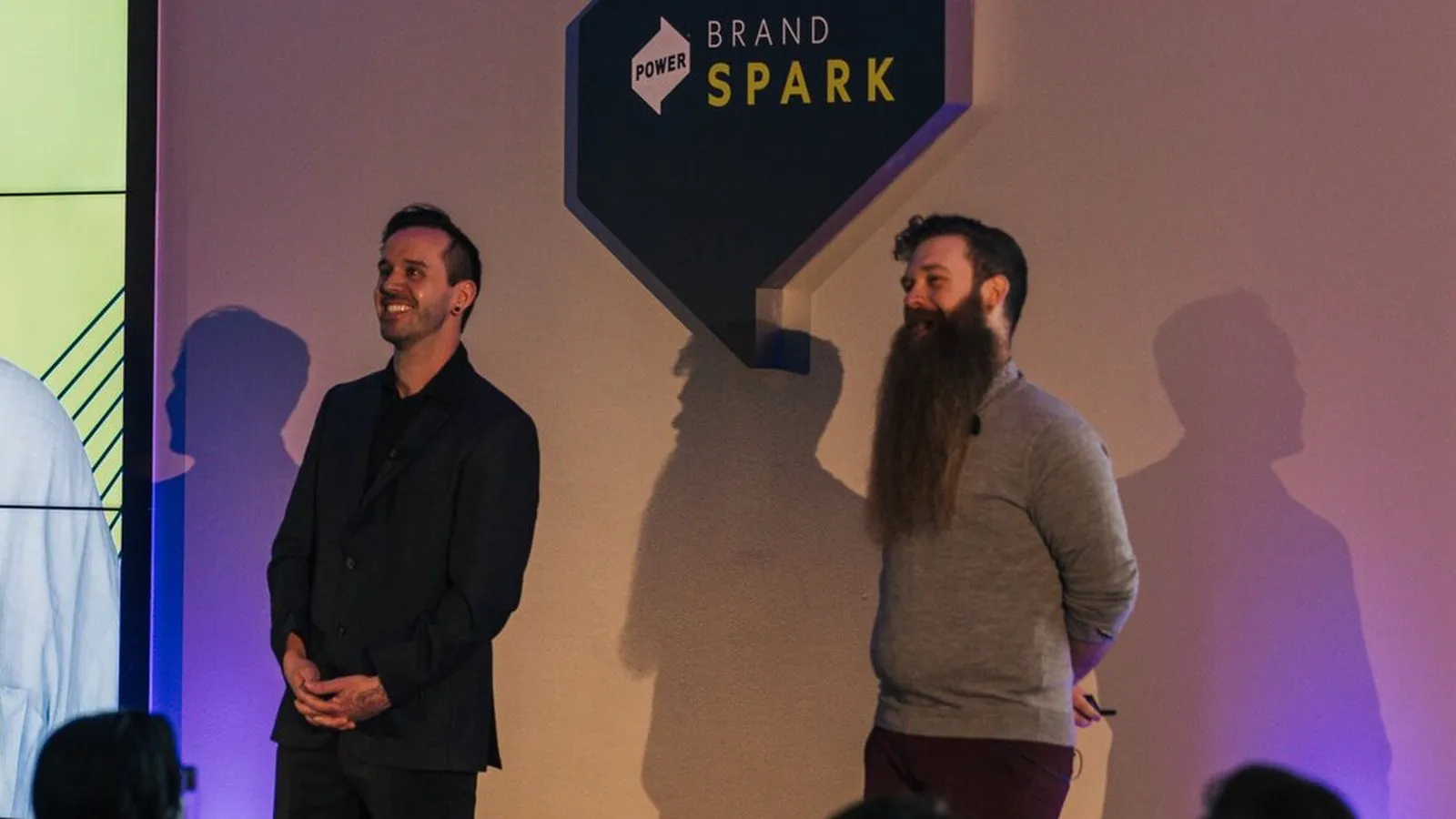 Matt and Adam Gotter-Fulton on stage at Brand Spark 2024, Matt smiling, the Brand Spark sign between them