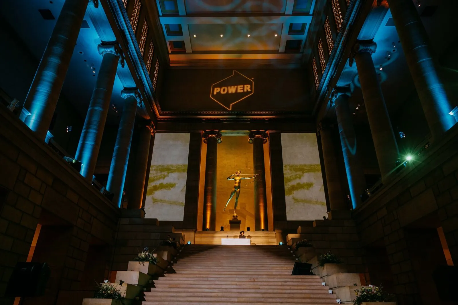 The stair hall from the foot of the stairs, a loop on each pillar and the huntress between them