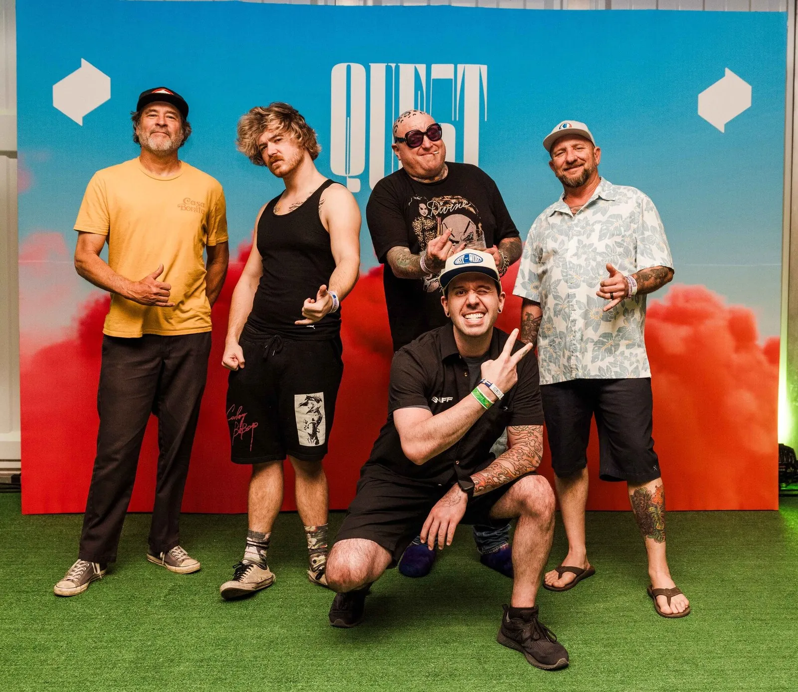 Matt with Sublime backstage at Quest 2024, crouched at the front in front of the Quest backdrop